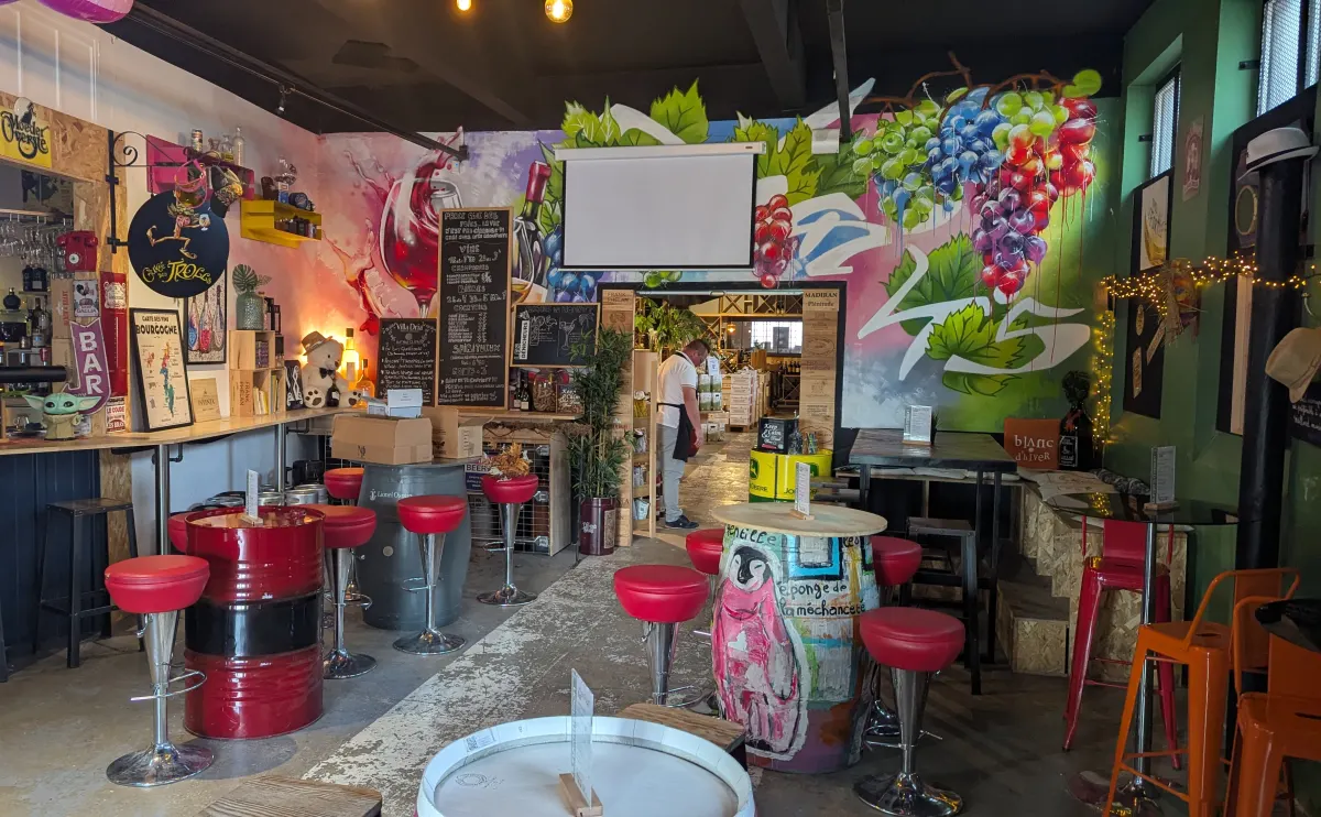 Le bar et la salle d'Urban Food au Chai N°5 : tabourets rouges, tonneaux peints et fresque de vignes